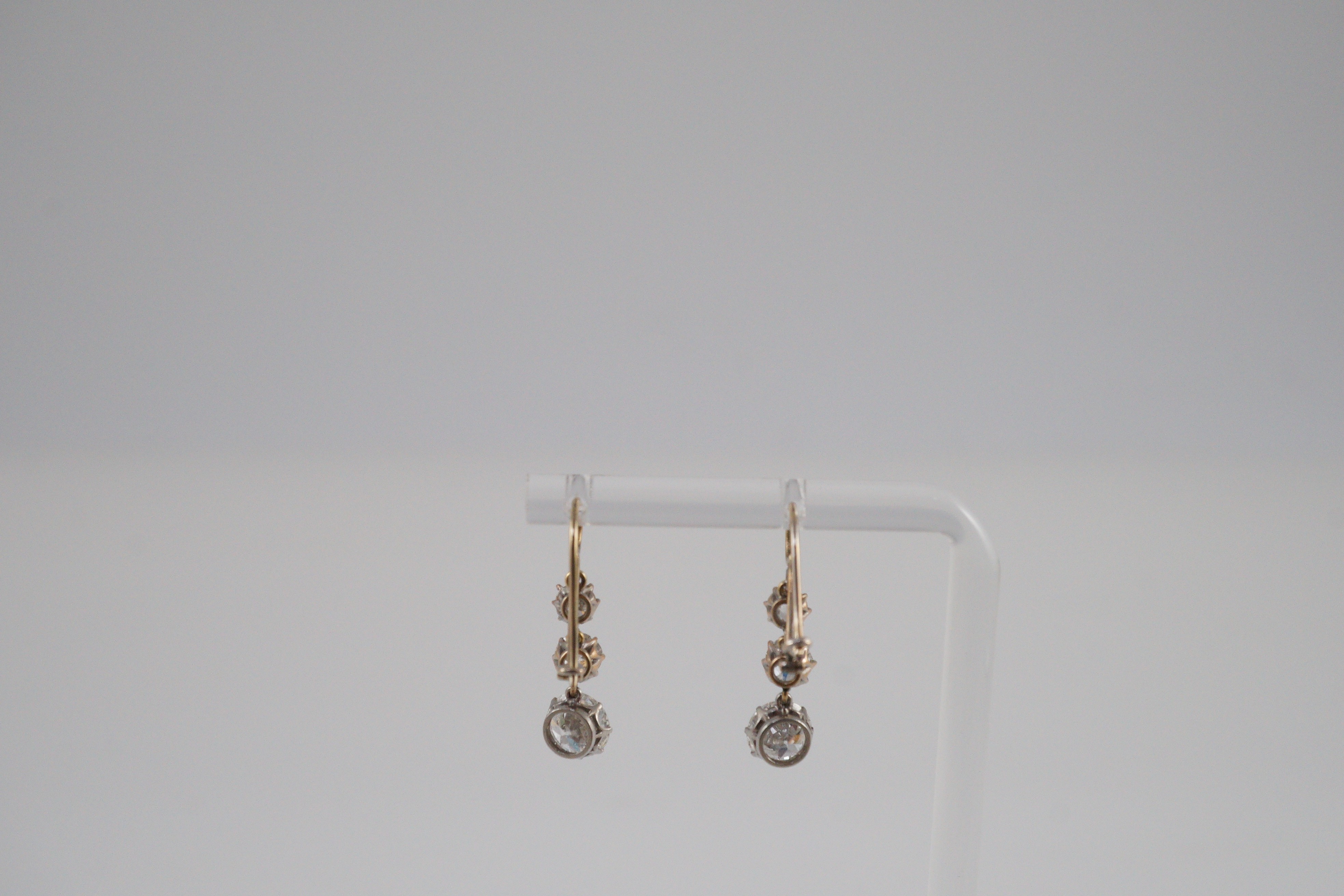 A pair of early to mid 20th century gold, platinum and graduated three stone diamond set drop earrings